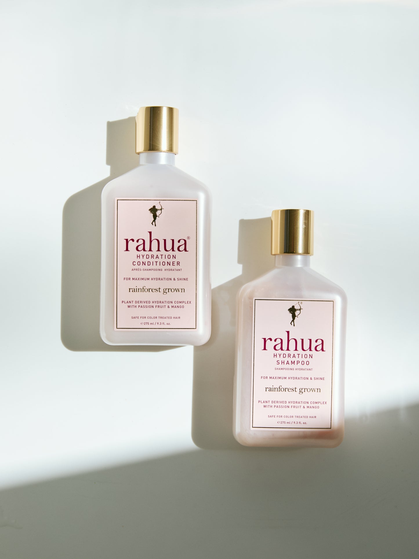 two bottles of rahua hair care hydration shampoo and conditioner plastic bottles with gold caps on a white background|variant:93-oz