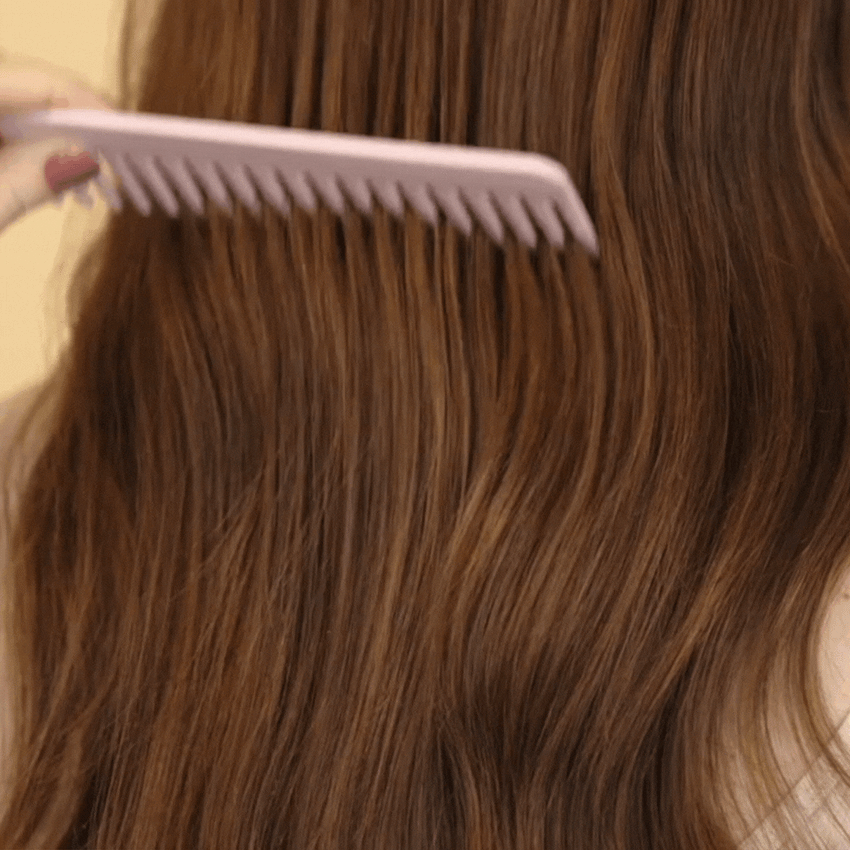 model brushing wavy brown hair through with a wooden comb|variant:65-oz