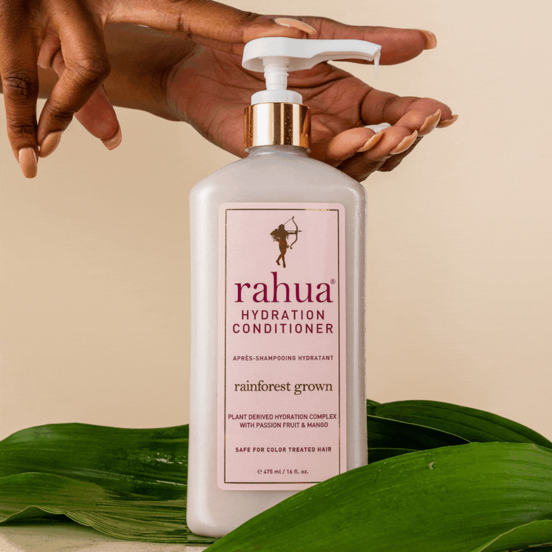 gif of rahua hydration conditioner 16 oz lush pump pumping product onto a model's hand bottle is sitting on top of a leaf|variant:16-oz