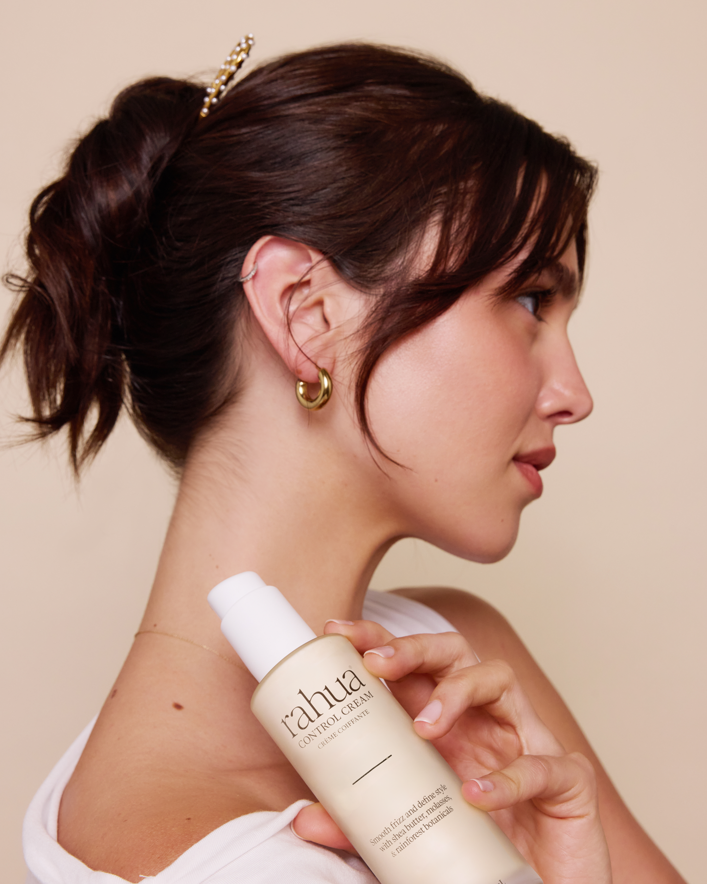 Woman holding a bottle of 'Fahua' skincare product against a beige background