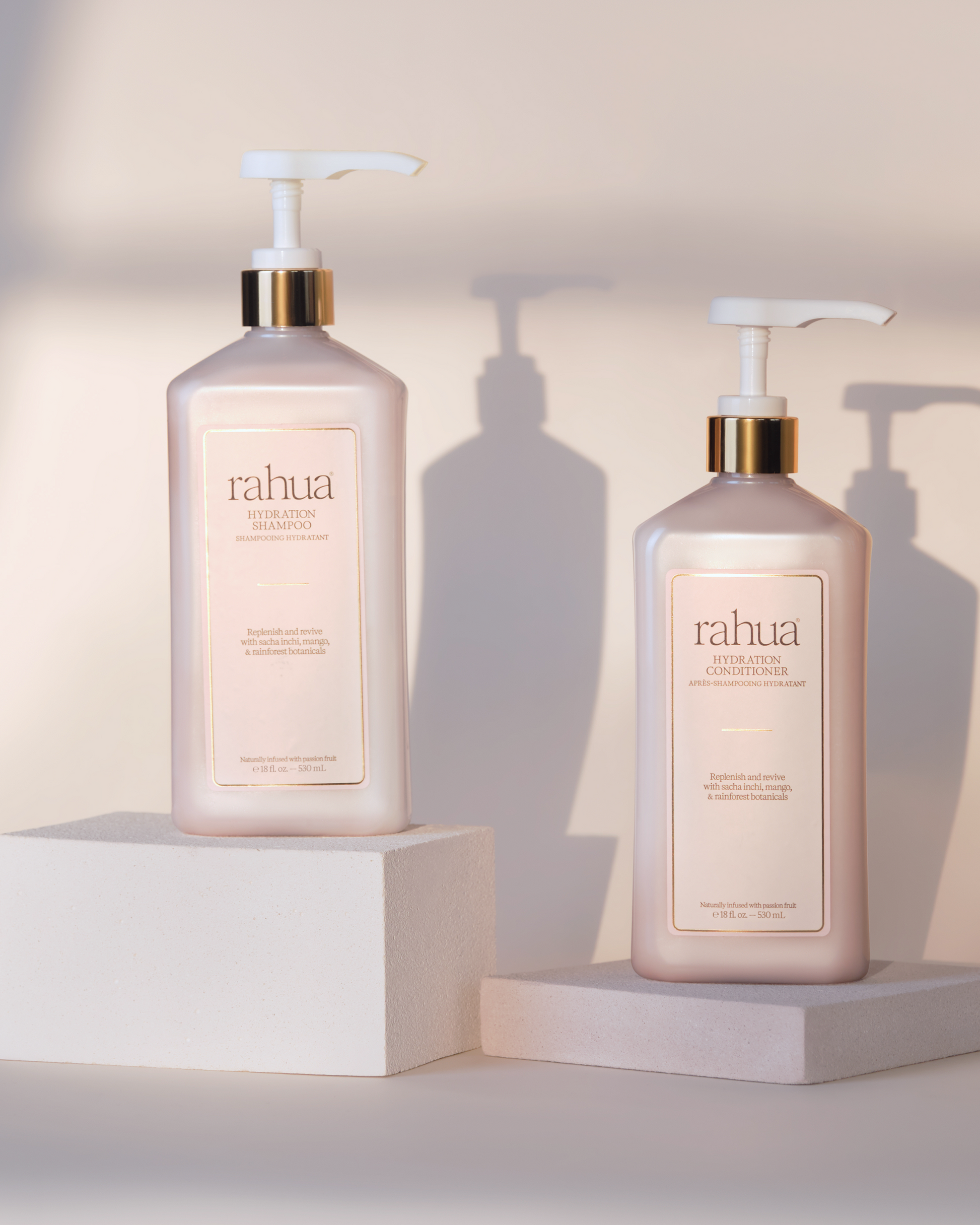Two Rahua hair care products on white stands with a neutral background|variant:16-oz