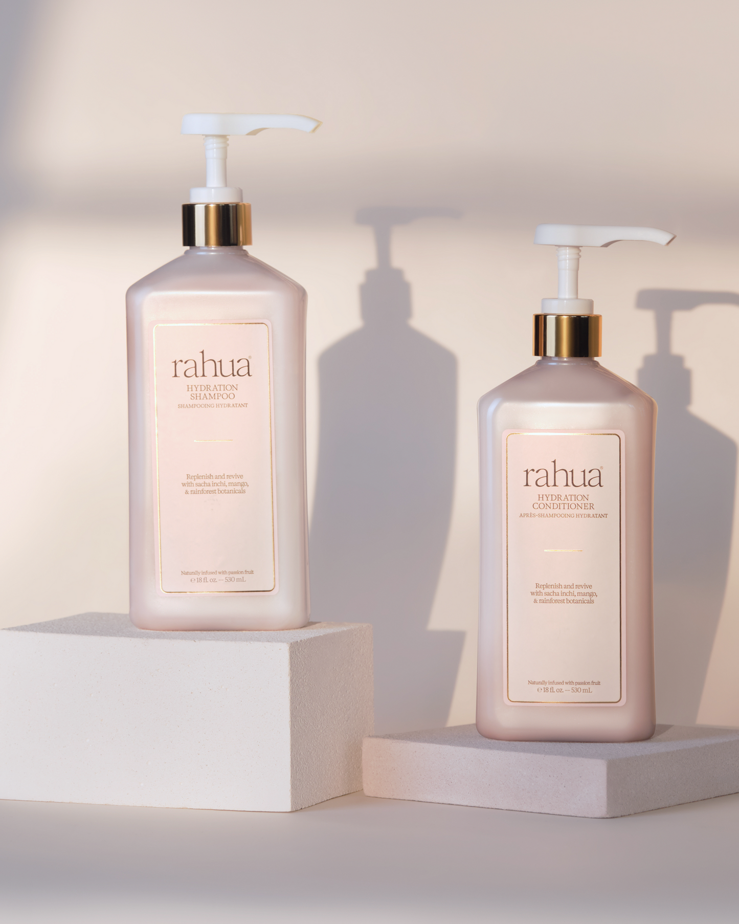 Two Rahua hair care products on white stands with a neutral background|variant:18-oz