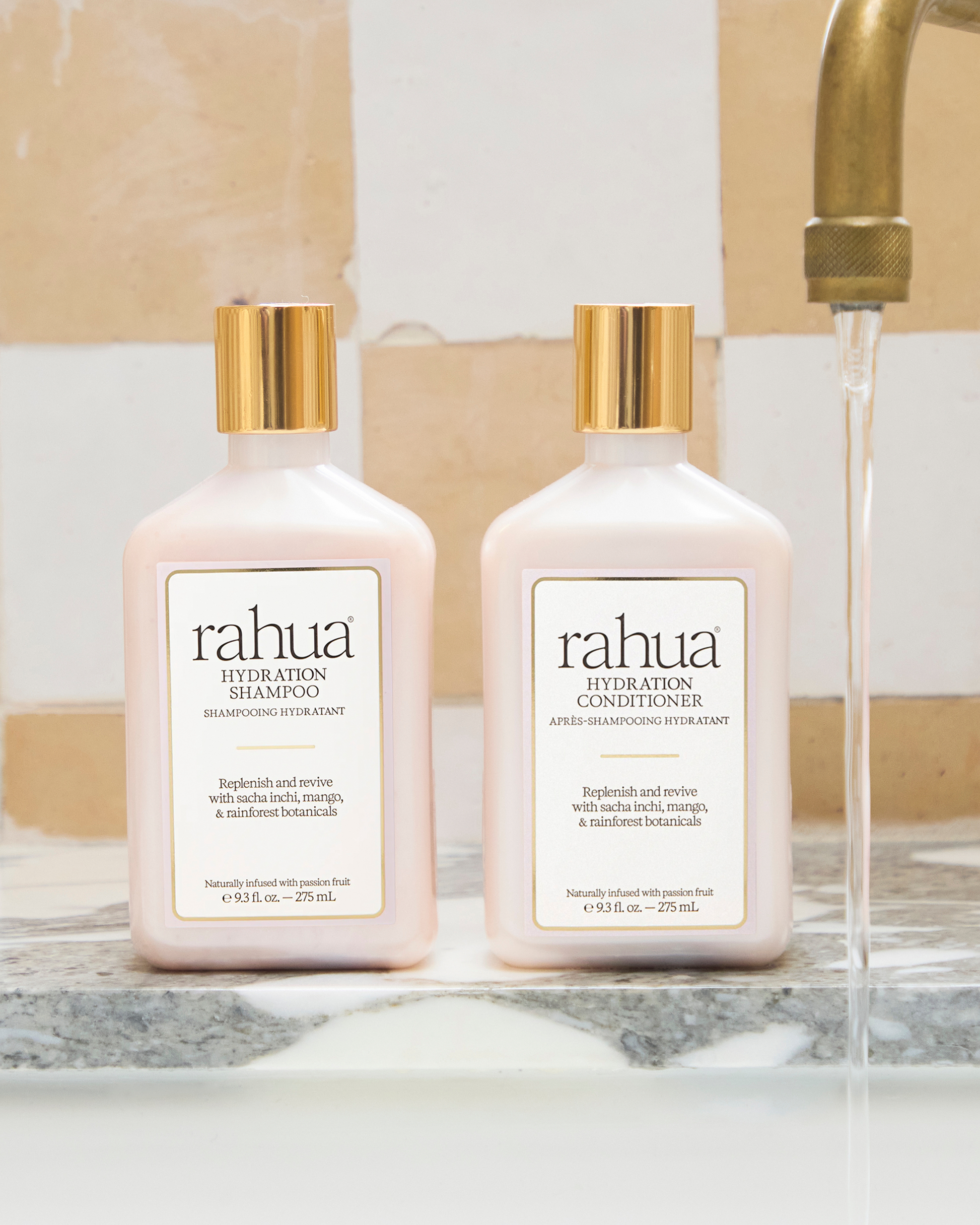Two bottles of rahua shampoo and conditioner on a marble surface with a blurred background.|variant:93-oz